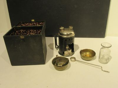 une cafetière, une tasse, une cuillère et un récipient posés sur une table