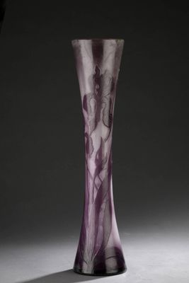 un vase en verre violet posé sur une table blanche près d'un mur noir