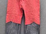 un vieux pantalon rouge accroché à un porte-vêtements