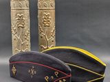 two military hats are sitting next to each other on a gray surface