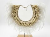 un gros plan d'un collier orné de plumes, posé sur un support en bois