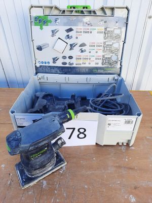 une ponceuse électrique et une boîte à outils posées sur une table en bois