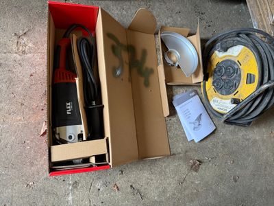 une boîte posée par terre et contenant quelques outils