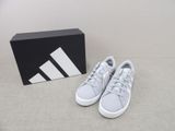 Les chaussures Adidas sont par terre, à côté d'une boîte.