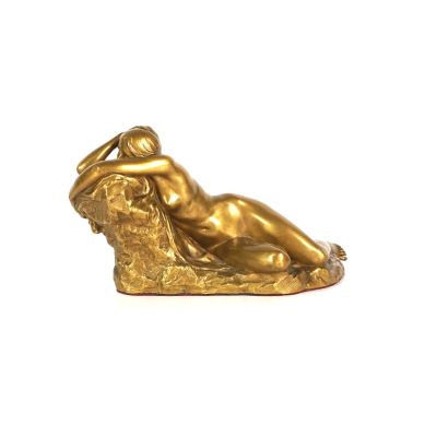 statue d'une femme allongée sur un oreiller, posée sur une surface blanche