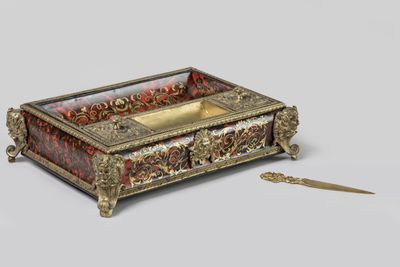 une boîte dorée et rouge posée sur une table à côté d'une paire de ciseaux