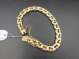 gros plan d'un bracelet en chaîne en or sur une surface noire
