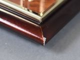 close up of a wooden and brass clock on a table