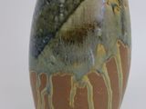 a brown and green vase sitting on a white surface