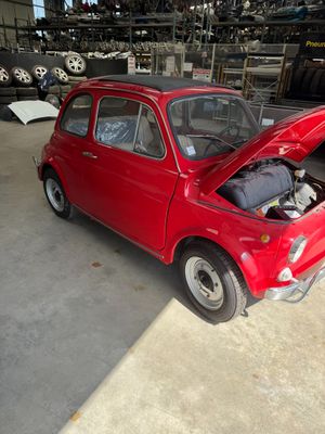 une petite voiture rouge, le capot ouvert, dans un garage