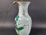 a green vase with a gold handle on a table