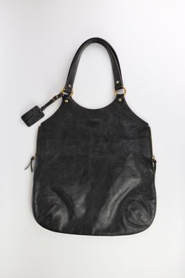 un sac à main en cuir noir accroché à un mur blanc