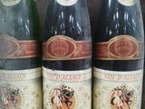 four bottles of wine are lined up on a shelf