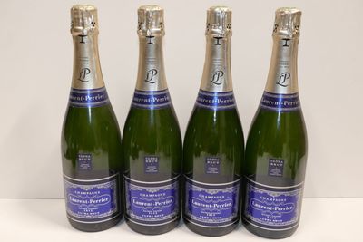 four bottles of sparkling wine are lined up on a table