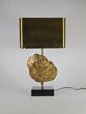 une lampe à feuille d'or sur un pied noir, avec un abat-jour doré