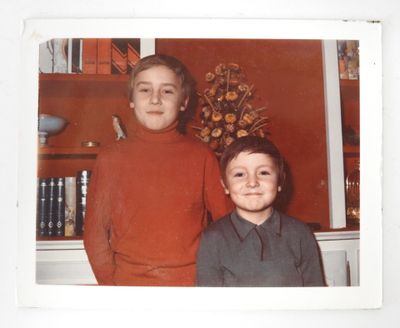 two young boys standing next to each other in front of a book shelf