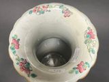 a small white vase with a floral design on it