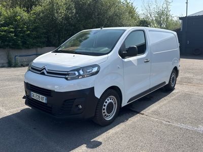 la camionnette blanche est garée sur un parking avec des arbres en arrière-plan