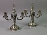 Deux chandeliers en argent sont posés l'un à côté de l'autre sur une table.