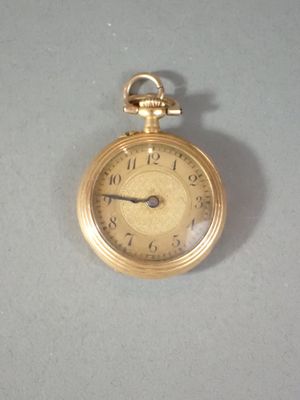 a gold pocket watch on a table with a white background