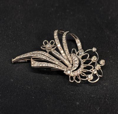 un gros plan d'une broche en argent sertie de diamants sur fond noir