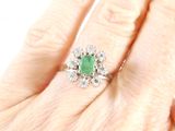 an image of a woman ' s hand with a diamond and emerald ring