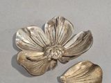 silver plated flower and leaf broochs on a gray surface