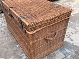 a wicker trunk sitting on the floor in front of a cabinet