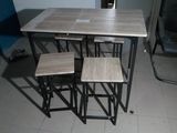 une table avec quatre tabourets et une chaise à côté