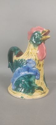 un petit coq en céramique posé sur une surface grise