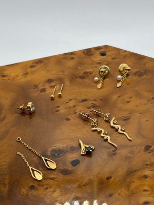 une boîte en bois sur laquelle sont posées plusieurs paires de boucles d'oreilles