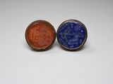 two rings with blue and orange stone in them on a white surface