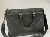 a green leather bag with a black strap on a white background