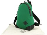 a green backpack sitting on top of a white towel