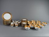 a group of gold and white dishes and cups on a table