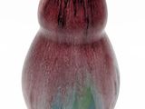 un vase rouge orné d'un motif vert et bleu