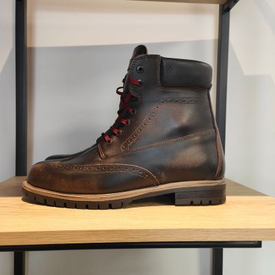 des bottes en cuir marron avec des lacets rouges, posées sur une étagère dans un magasin