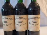 trois bouteilles de vin rouge posées sur une table blanche