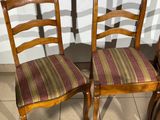 pair of wooden chairs with striped seat covers on them in front of a white wall