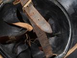 an old helmet with a leather band and a knife sticking out of it