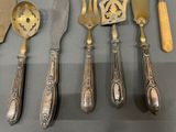 a lot of silverware on a table with a knife, spoon, and spoon rest