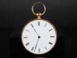 une image représentant une montre de poche en or posée sur une surface noire
