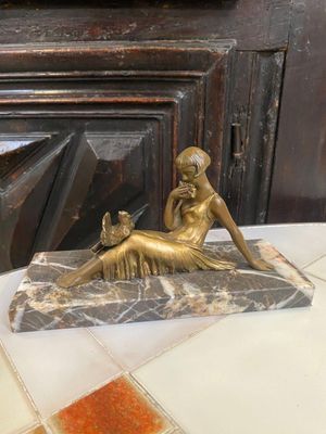 une statue représentant une femme assise sur un bloc de marbre