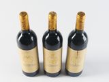 three bottles of wine sitting next to each other on a white surface