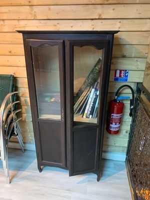 une armoire avec une porte vitrée et une chaise placée devant