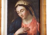 un tableau représentant une femme en robe rouge, les mains jointes