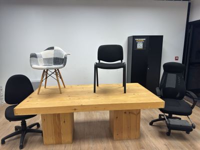 chairs and a table in a room with a refrigerator in the background