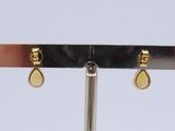 pair of gold tear shaped earrings on a black metal stand