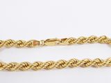 a gold rope bracelet with a clasp on a white background