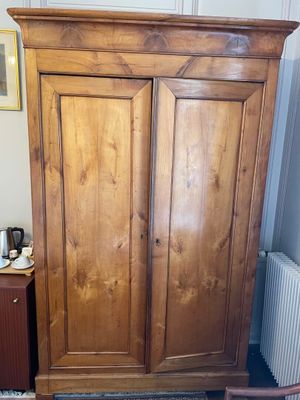 a wooden armoire in the corner of a room